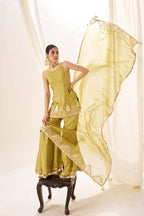 Woman in a green traditional outfit with a sheer dupatta in a minimalistic setting