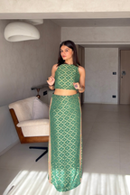 Woman in a green patterned outfit standing in a modern room.