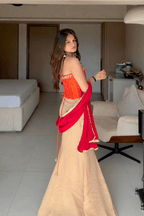 Woman in a red and beige traditional outfit standing in a modern living room.