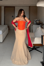 Woman in a red and beige traditional outfit standing in a living room.